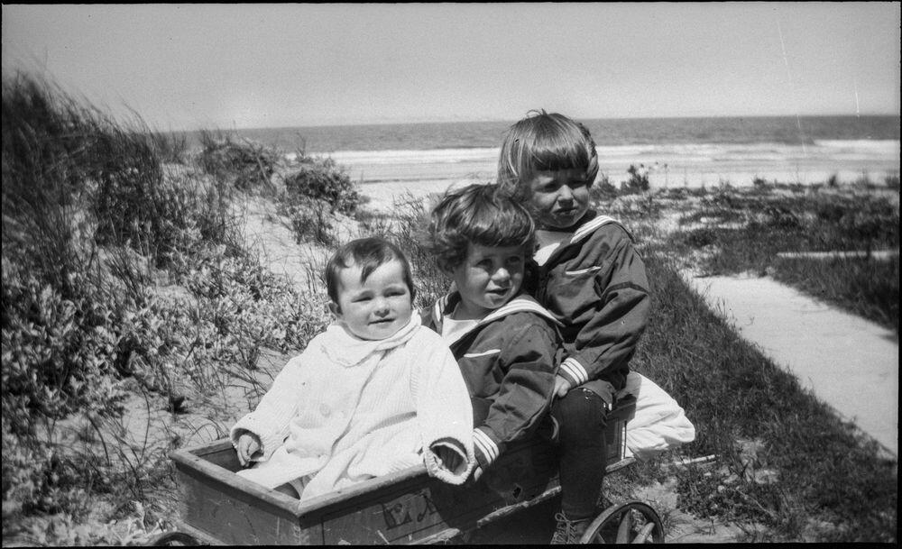 A 1919 photo of (L-R) Rosemary Kennedy, John F. Kennedy, and Joseph P. Kennedy, Jr. in a wagon at Nantasket Beach. Copyright © John F. Kennedy Library Foundation.