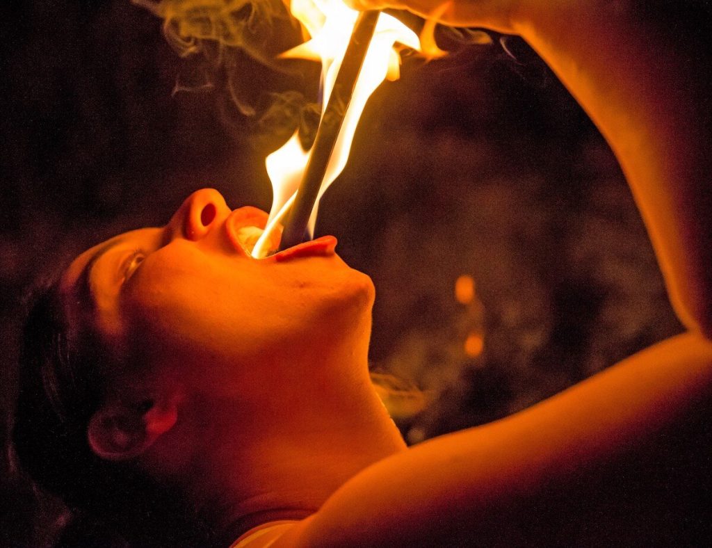 Skilled like Jo Girardelli, Sword-swallower Samantha Jones places a fire wand in her mouth. Image: Jayson Mellom.