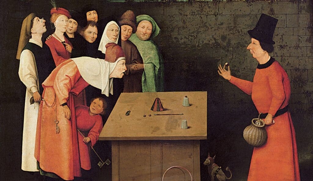 A magician performs a cup trick while a man steals the money purse of a spectator, c 1475, <em>The Conjurer</em> by Hieronymus Bosch.