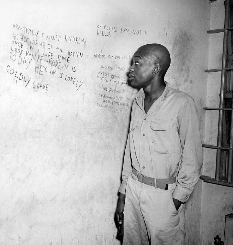 Willie viewing the writing on the prison wall. His head is shaved in preparation for the electric chair.