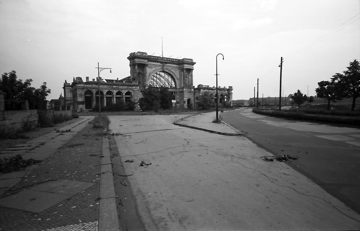 The arched stone facade of the disused Lehrter railway station in West Berlin, seen across an empty street in 1957