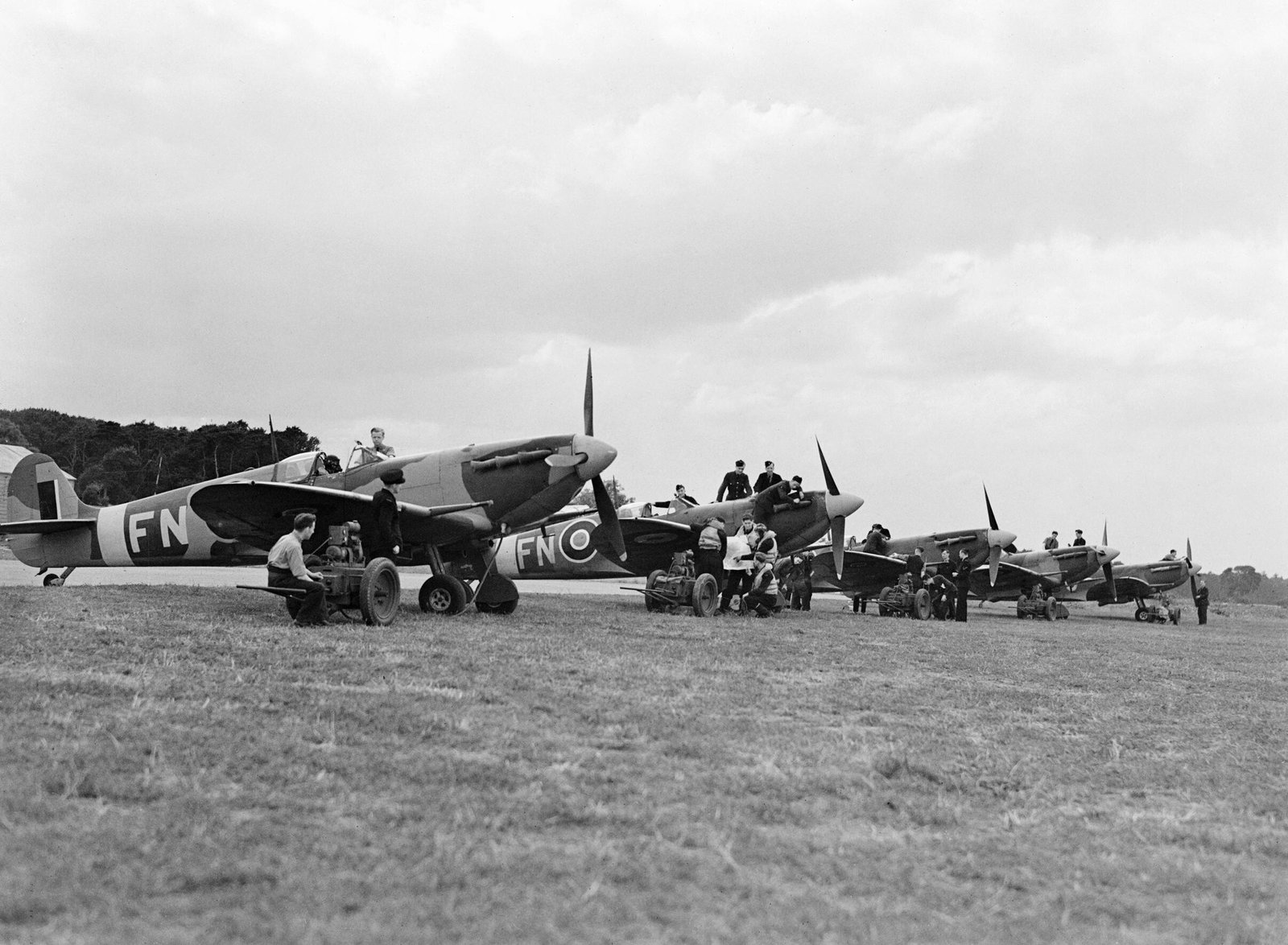 A line of Spitfire fighters with ground crew on the grass airfield at RAF Drem in East Lothian, Scotland, in 1942